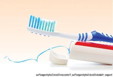 Photo of a toothbrush and toothpaste on a light orange gradated background
